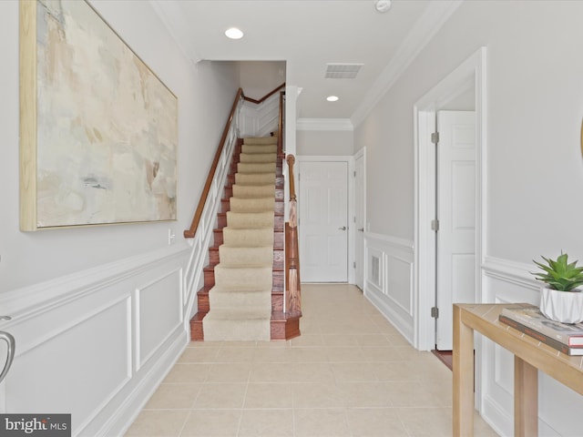 stairway with tile patterned floors and crown molding