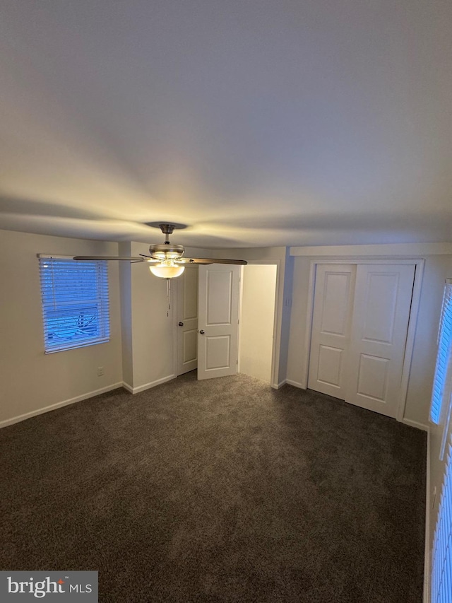 unfurnished bedroom with ceiling fan and dark colored carpet