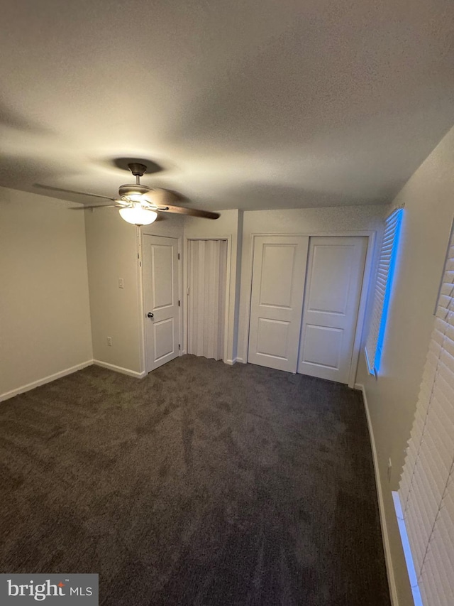 unfurnished bedroom featuring ceiling fan, a textured ceiling, and dark colored carpet