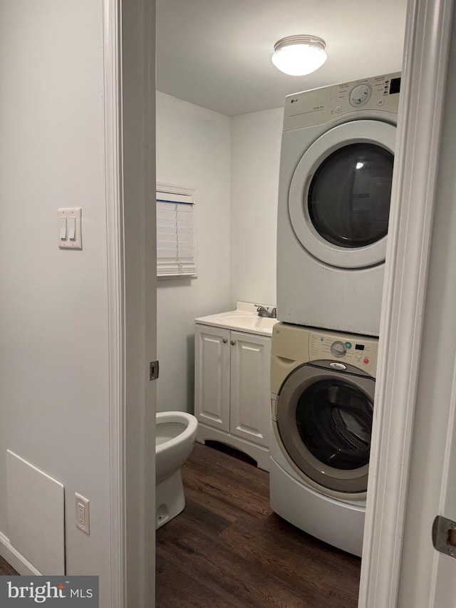 washroom with dark wood-type flooring, stacked washer / drying machine, and sink