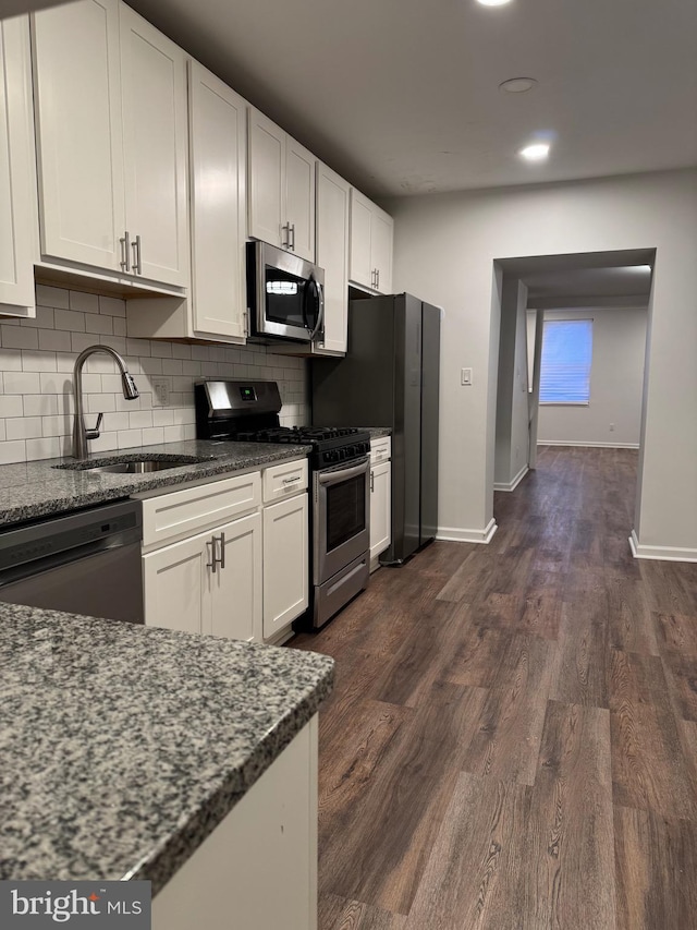 kitchen featuring sink, white cabinets, dark stone counters, and black appliances