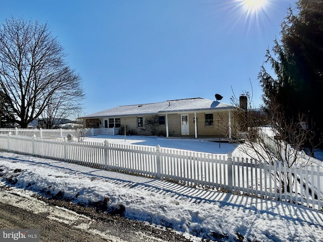 snow covered house with a fenced front yard