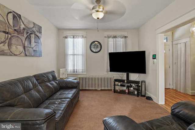 carpeted living room with ceiling fan and radiator