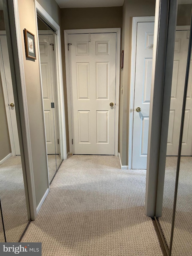 hall with baseboards and light colored carpet