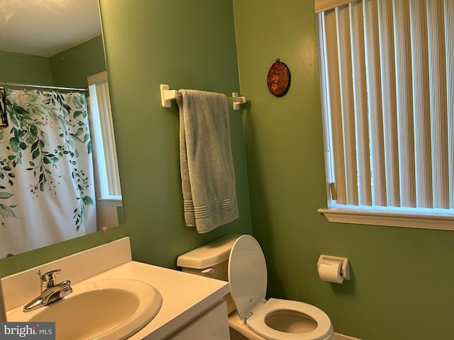 full bath featuring a shower with shower curtain, toilet, and vanity