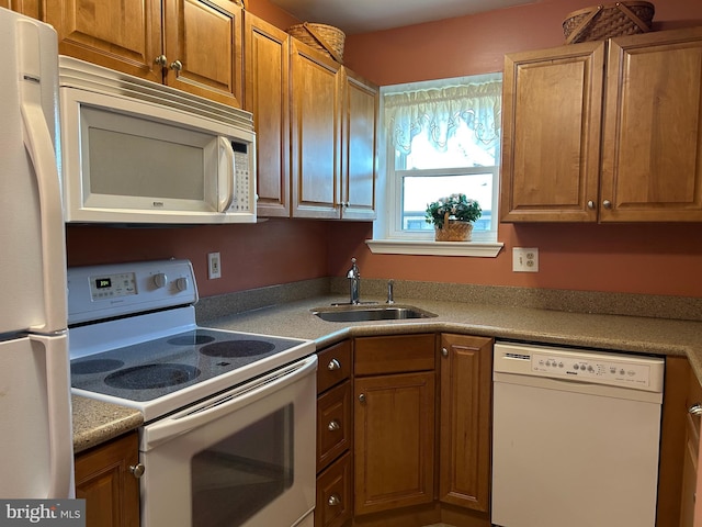 kitchen featuring white appliances, brown cabinets, and a sink