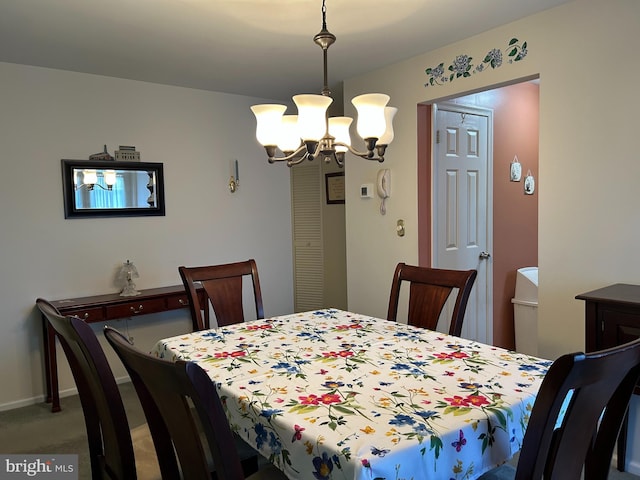 carpeted dining space featuring baseboards and a chandelier