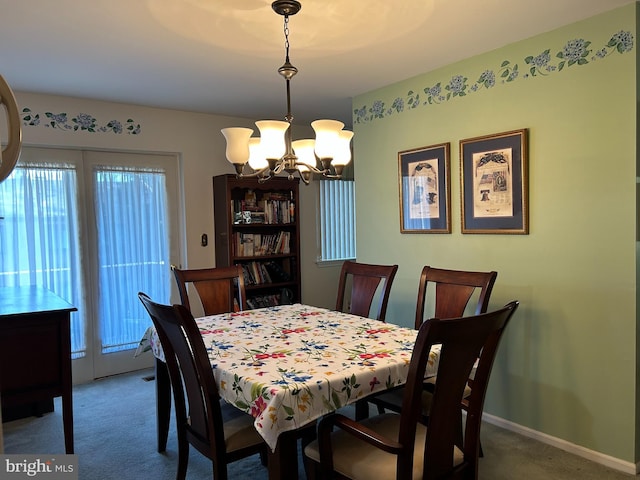 carpeted dining area featuring a chandelier and baseboards