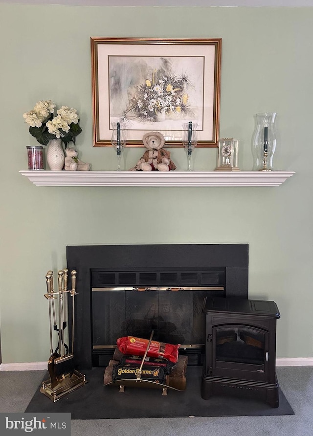 room details with carpet flooring, a wood stove, baseboards, and a glass covered fireplace