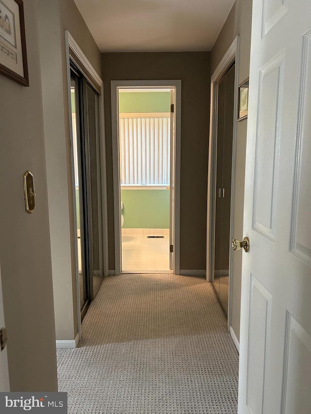 hall with baseboards and carpet flooring