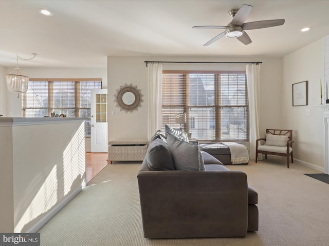 carpeted living room featuring a healthy amount of sunlight and ceiling fan with notable chandelier