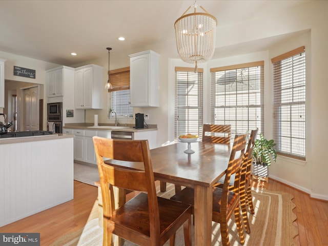 dining room featuring sink, an inviting chandelier, and light hardwood / wood-style flooring