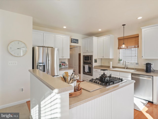 kitchen featuring sink, white cabinetry, a center island, hanging light fixtures, and stainless steel appliances