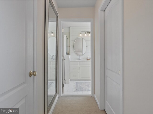 corridor featuring sink and light colored carpet