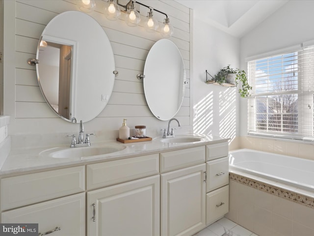 bathroom with vanity, vaulted ceiling, and tiled bath