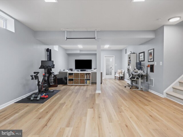 workout area with rail lighting and light hardwood / wood-style flooring