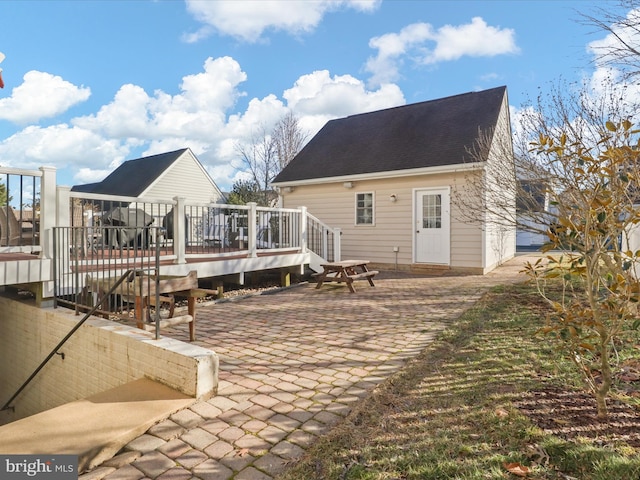 back of property with a wooden deck and a patio