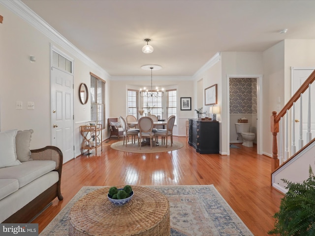 living room featuring crown molding, a chandelier, and light wood-type flooring