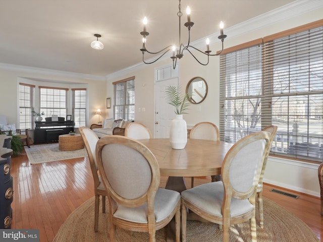 dining space with ornamental molding and light hardwood / wood-style flooring