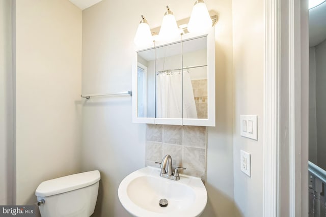 bathroom with toilet, a shower with curtain, tasteful backsplash, and sink