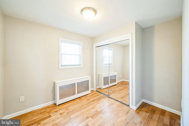 unfurnished bedroom with radiator, a closet, and wood-type flooring