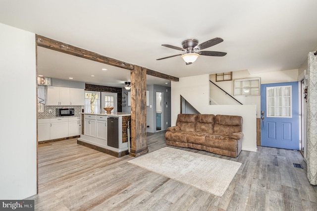 living room featuring ceiling fan, light hardwood / wood-style floors, and beamed ceiling