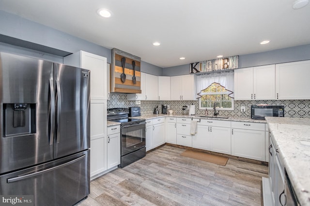 kitchen featuring white cabinets, light stone countertops, black appliances, light hardwood / wood-style flooring, and sink