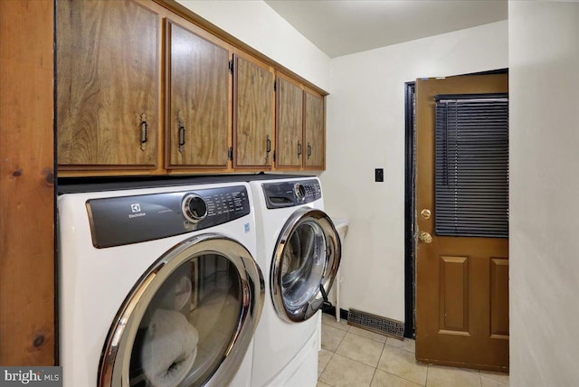 clothes washing area with cabinets, light tile patterned floors, and independent washer and dryer