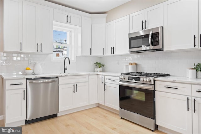 kitchen with stainless steel appliances, backsplash, white cabinets, and sink