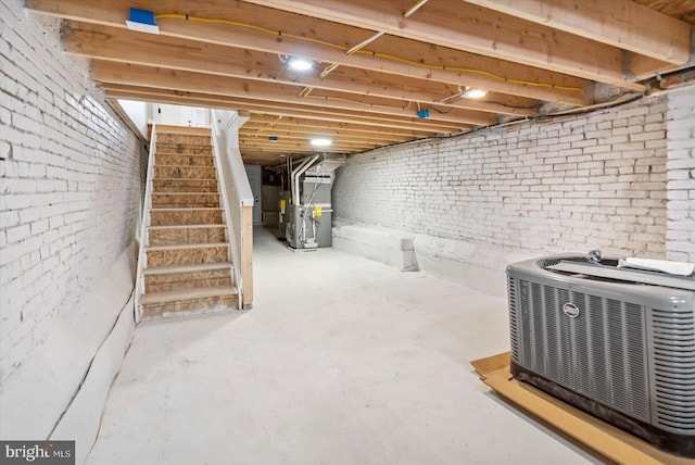 basement featuring heating unit and brick wall