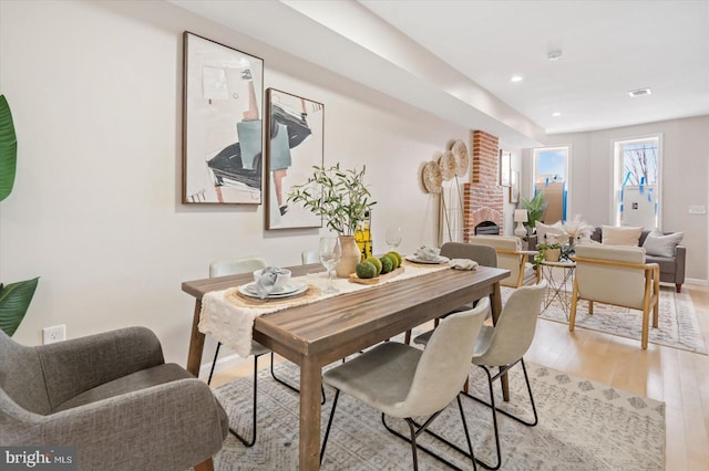 dining area featuring a brick fireplace and light hardwood / wood-style flooring