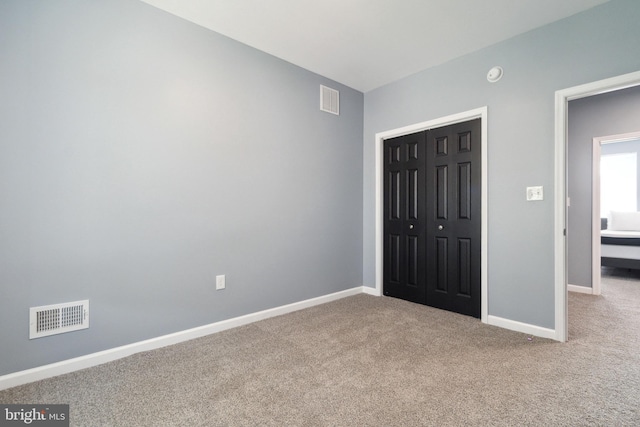 unfurnished bedroom featuring light carpet and a closet