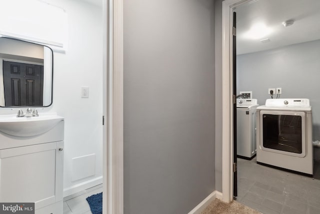 clothes washing area featuring light tile patterned flooring, washing machine and clothes dryer, and sink