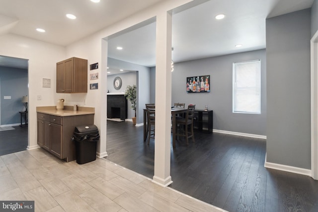 kitchen featuring a brick fireplace and dark brown cabinets