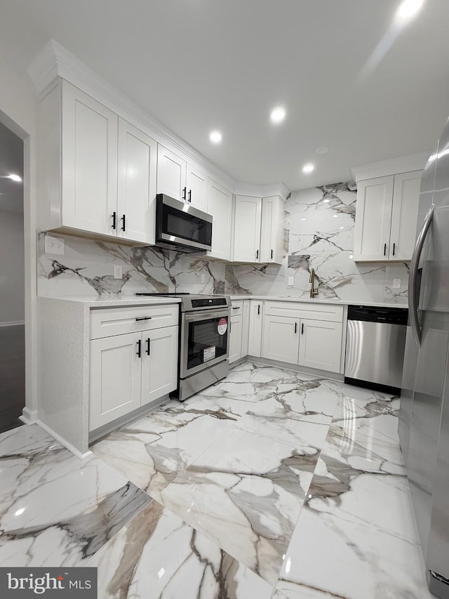 kitchen featuring sink, appliances with stainless steel finishes, light stone counters, white cabinets, and decorative backsplash