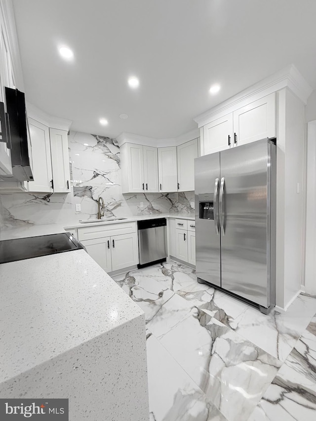 kitchen with sink, appliances with stainless steel finishes, white cabinetry, backsplash, and light stone countertops