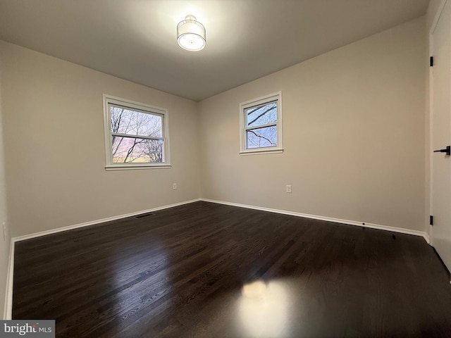 unfurnished room featuring dark wood-type flooring and a healthy amount of sunlight