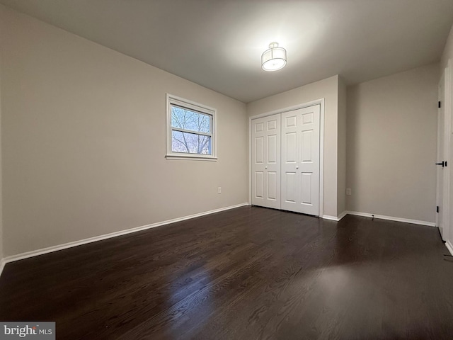 unfurnished bedroom with dark hardwood / wood-style floors and a closet