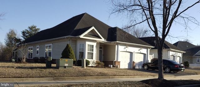 view of side of home with a garage, brick siding, and driveway