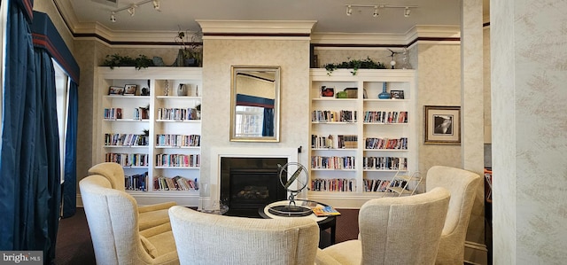 living area with built in shelves, track lighting, ornamental molding, and a fireplace