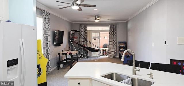 kitchen featuring ornamental molding, white refrigerator with ice dispenser, light countertops, and a sink