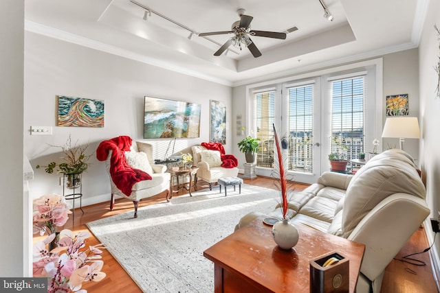 living room with hardwood / wood-style floors, ornamental molding, ceiling fan, a raised ceiling, and track lighting