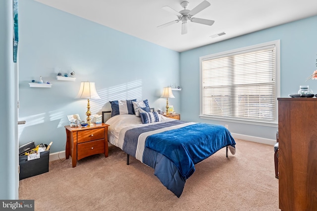 bedroom with multiple windows, light colored carpet, and ceiling fan