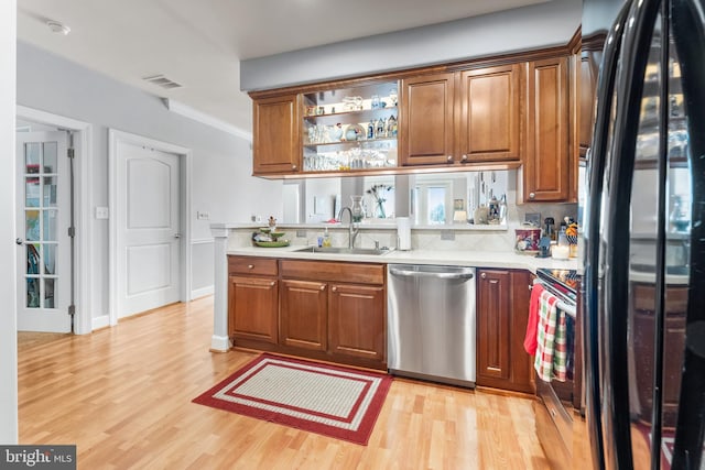 kitchen with crown molding, stainless steel appliances, sink, and light wood-type flooring