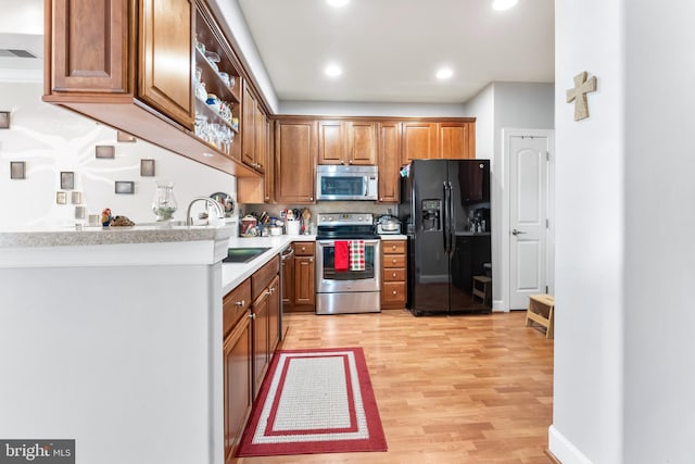 kitchen featuring stainless steel appliances, sink, backsplash, and light hardwood / wood-style flooring