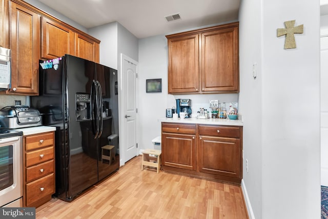 kitchen with stainless steel range, black fridge with ice dispenser, and light hardwood / wood-style floors