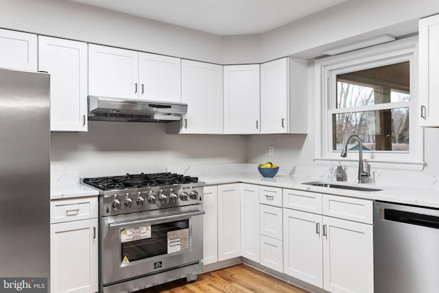 kitchen featuring white cabinetry, sink, stainless steel appliances, and light stone countertops