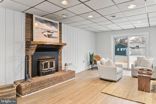 living room with hardwood / wood-style floors, a fireplace, and a paneled ceiling