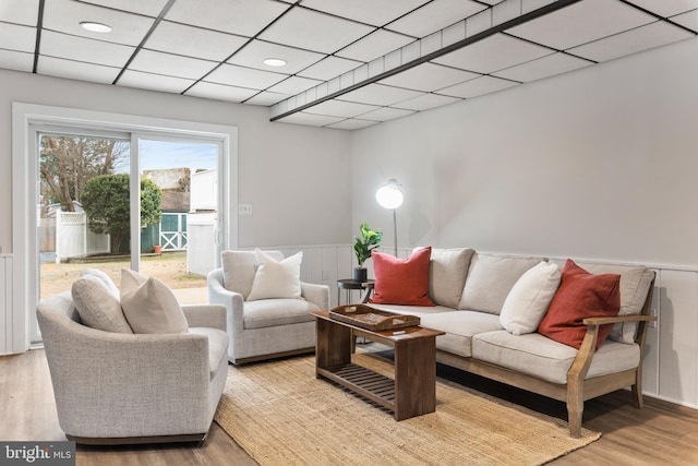 living room with a paneled ceiling and light hardwood / wood-style flooring