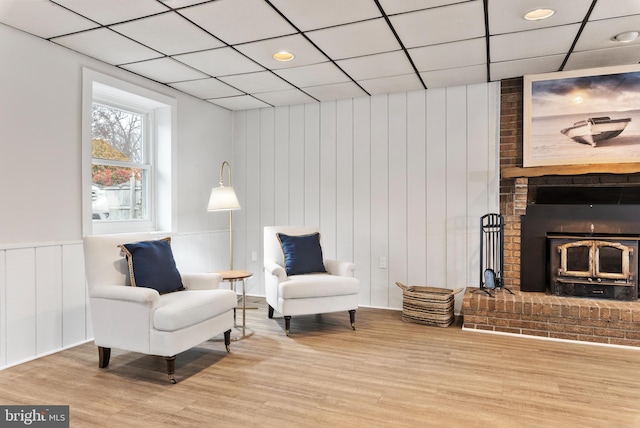 sitting room with hardwood / wood-style flooring, a drop ceiling, and a fireplace